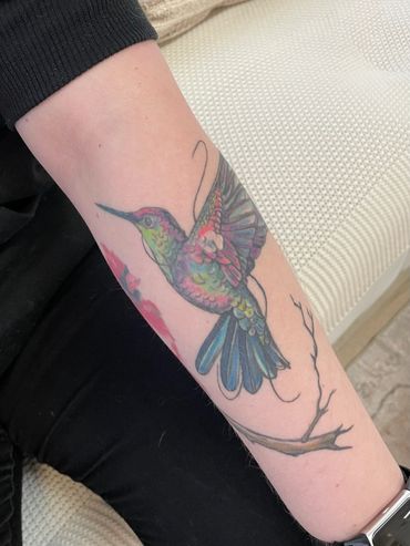 Colorful hummingbird tattoo on forearm.