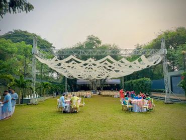 Outdoor event with canopy and people seated at tables.