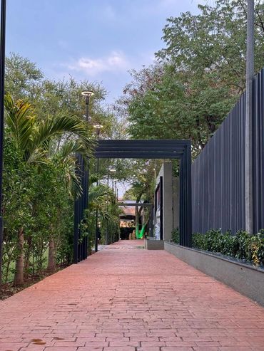 A serene pathway lined with greenery and modern black arches.