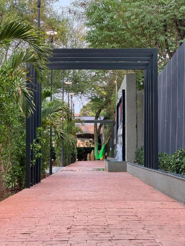 Pathway lined with plants and black metal archways in a park setting.