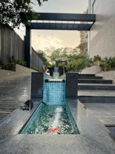 Modern outdoor water feature with cascading waterfall and tiled basin.