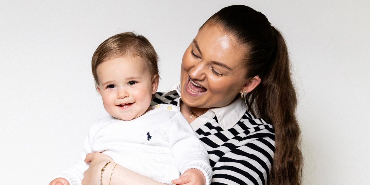 A woman happily holding a smiling baby.