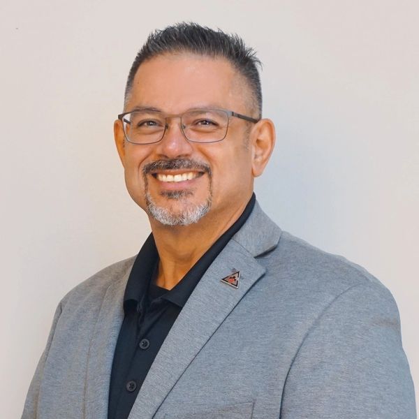Smiling man in glasses and gray blazer.