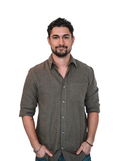 Man with beard in casual shirt, hands in pockets.