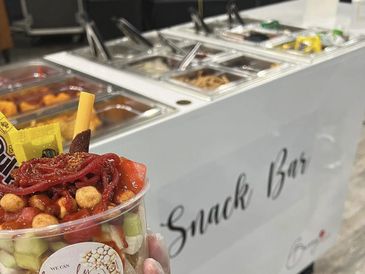 A colorful snack cup held in front of a snack bar counter.
