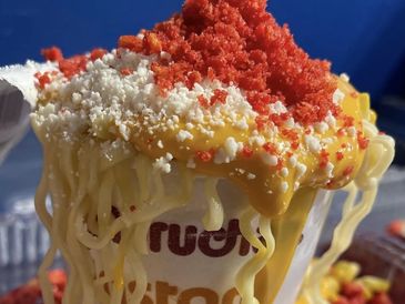 Instant noodles topped with cheese and red seasoning in a cup.