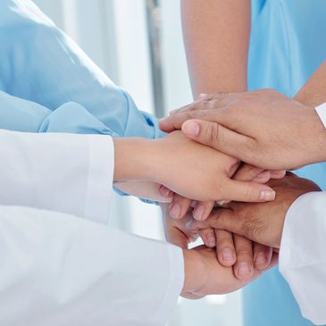Healthcare professionals joining hands in a teamwork gesture.