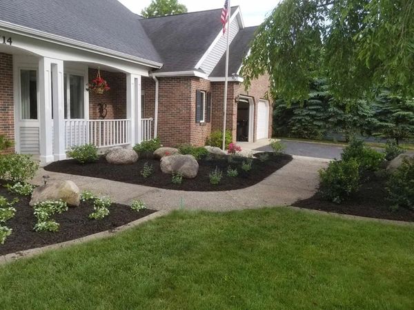Well-manicured front yard with mulch beds, shrubs, and rocks.