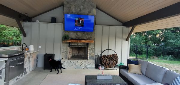 Cozy outdoor living space with fireplace, kitchen, and seating area.
