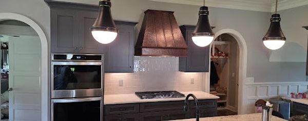Modern kitchen with dark cabinets, stainless steel oven, and pendant lights.