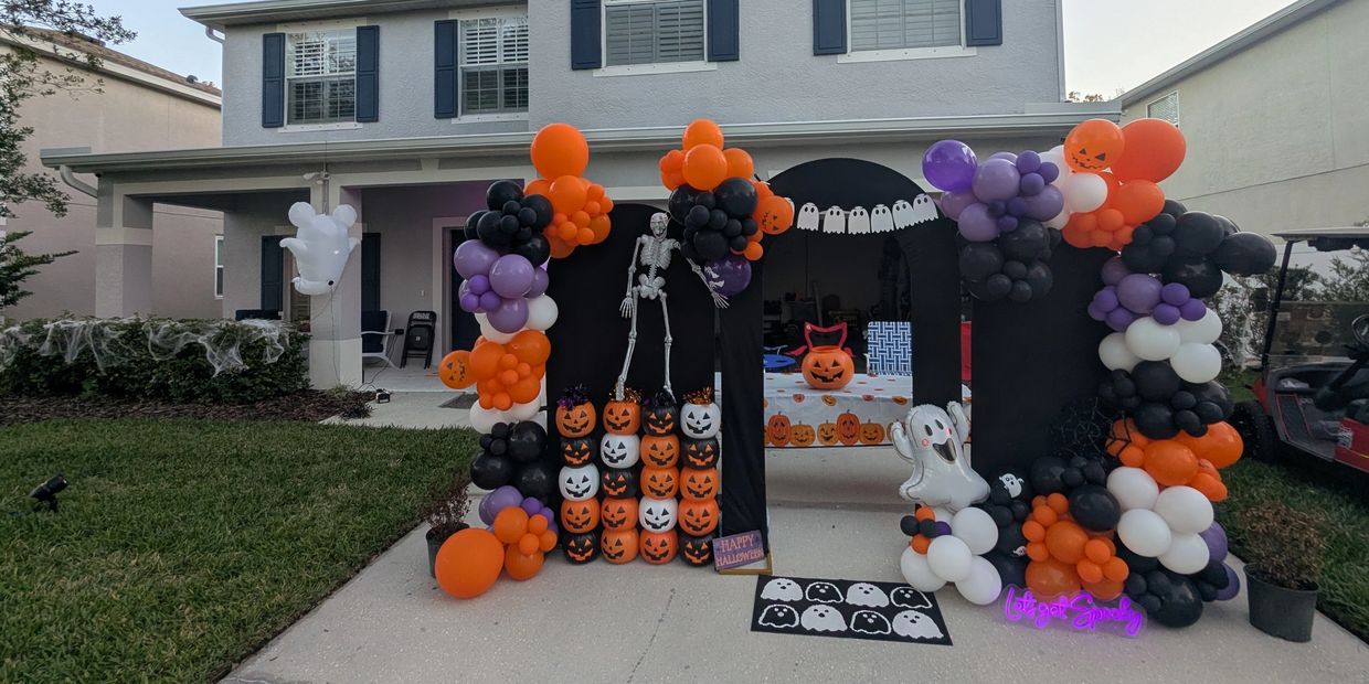 Halloween decorations with balloons and pumpkins in front of a house.