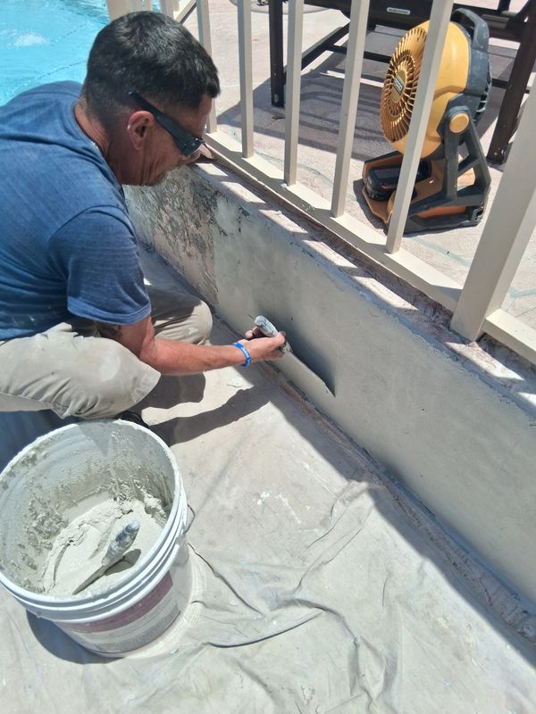 Man plastering wall near pool.