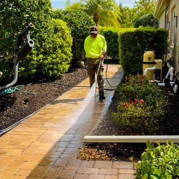 Man pressure cleaning brick paver pathway with a high pressure wand in Sarasota Florida