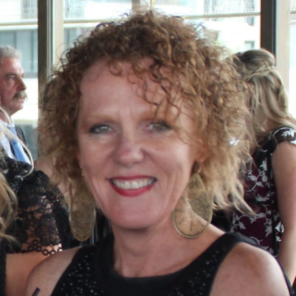 Smiling woman with curly hair and large earrings at an event.