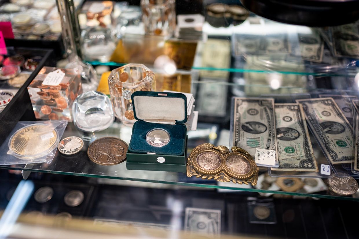 A collection of vintage coins and old currency bills displayed in a glass case.