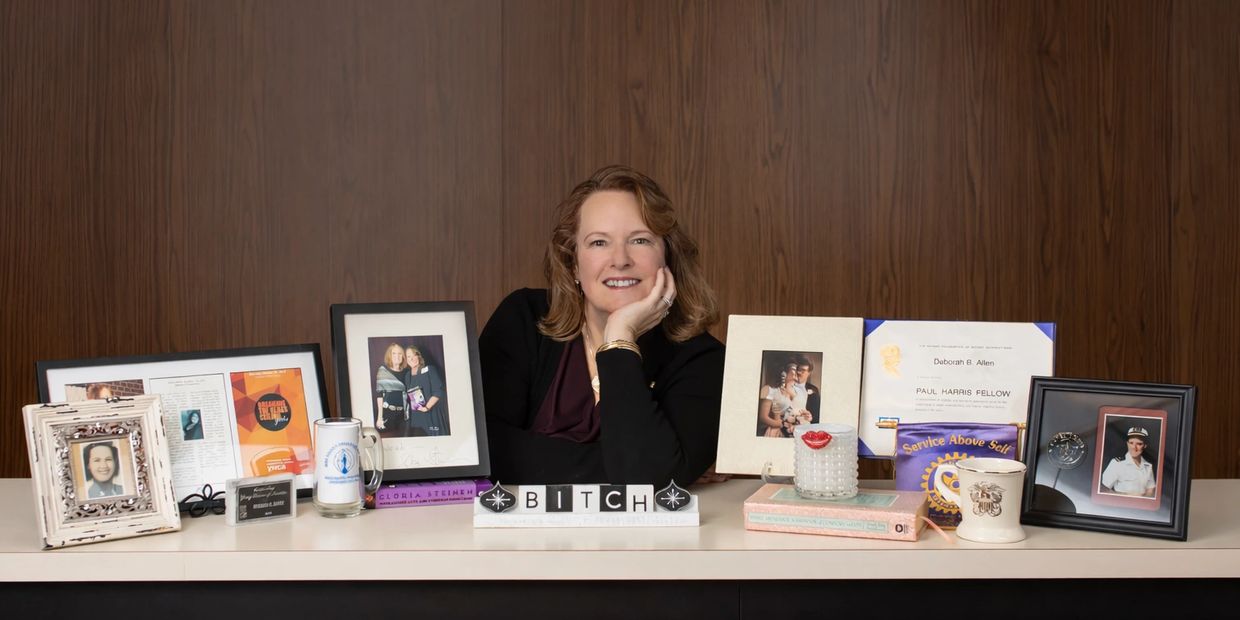 Woman smiling behind desk with framed photos and memorabilia.