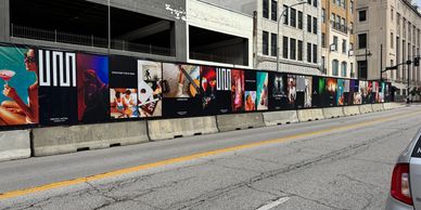 Colorful advertisements on a construction wall along an urban street.