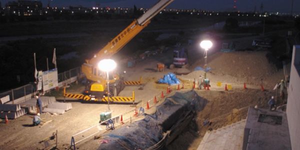 Nighttime construction site with crane and excavation area.