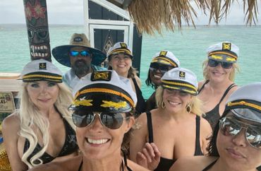 Group of friends wearing captain hats enjoying a tropical beach setting.