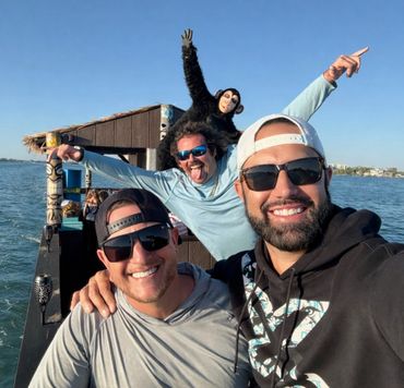 Three men smiling on a boat with a person in a monkey costume behind them.