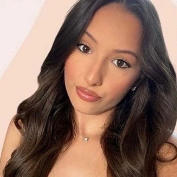 Young woman with long dark hair and natural makeup posing for a selfie.