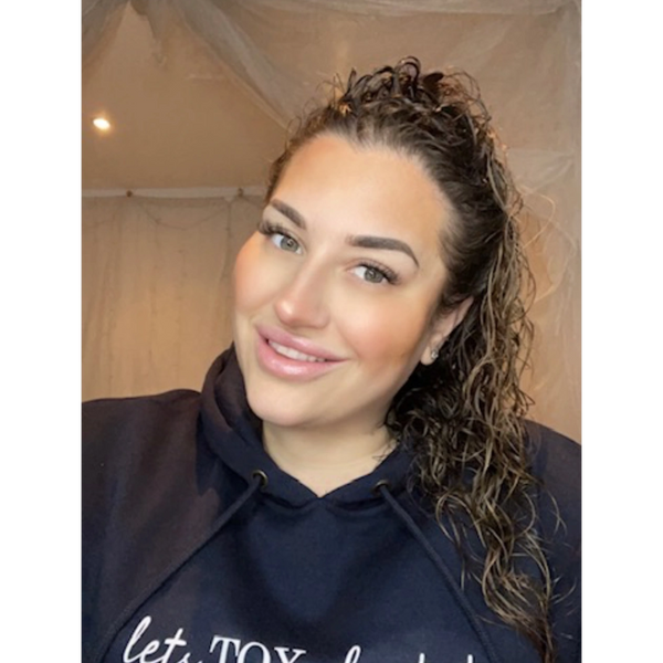 Smiling woman with curly hair in a dark hoodie.