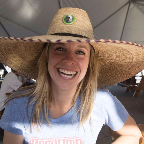 Smiling woman wearing a large straw hat indoors.