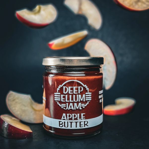 Jar of Deep Ellum Apple Butter surrounded by floating apple slices.