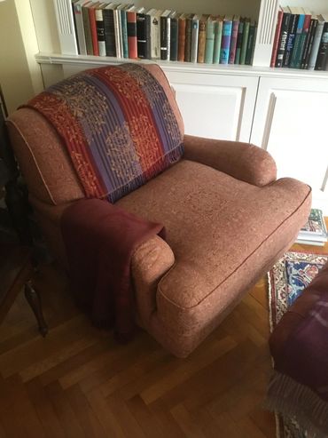 Cozy armchair with a colorful throw and a blanket in a reading corner.