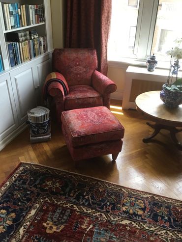 Cozy red armchair with ottoman in a sunlit reading nook.