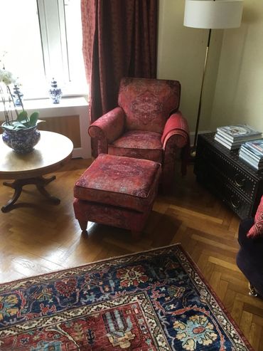 Cozy red armchair with ottoman in a warmly decorated room.