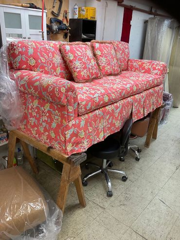 Floral red sofa on wooden sawhorses in workshop.