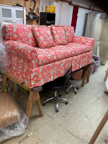 Red floral sofa elevated on a wooden stand.