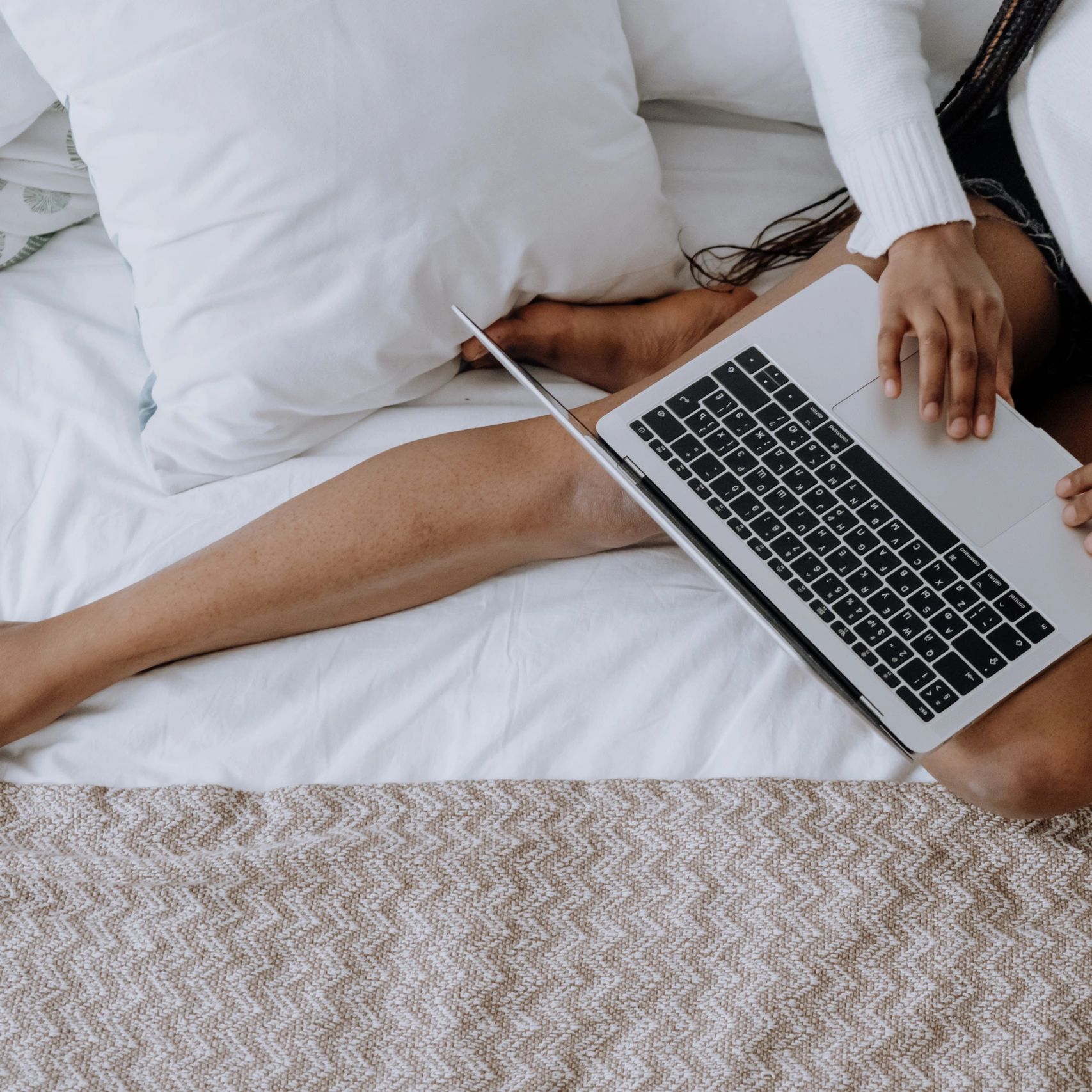 woman sitting on a bed with a laptop.