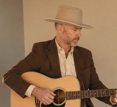 Man in a hat playing acoustic guitar.
