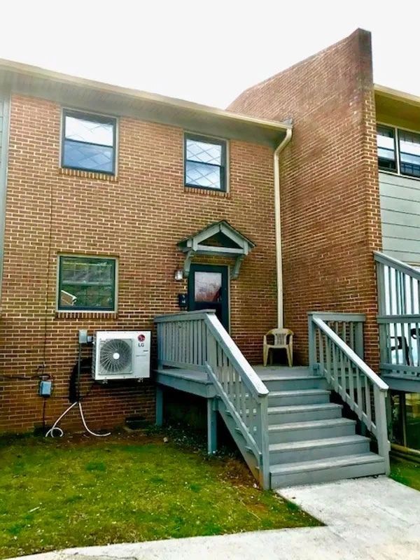 Brick house with gray stairs and a small porch chair.