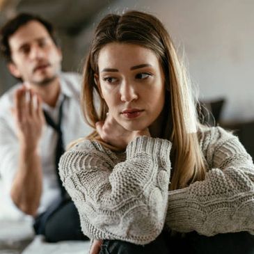 Woman looks upset while man talks in background.