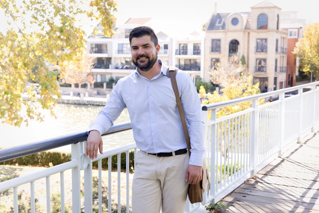 Man dressed in corporate attire leaning against a bridge