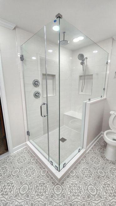 Modern glass shower with patterned tile flooring.