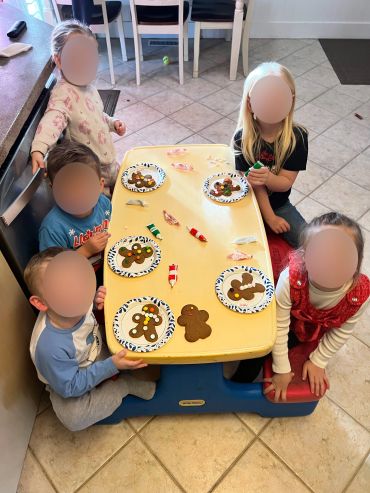 Kids decorating gingerbread cookies at a small table.