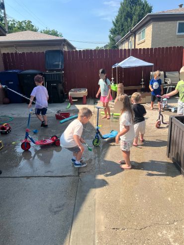 Kids playing with scooters in a backyard on a sunny day.
