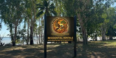 Signboard for Alnagith Corporation Residential Rentals in a wooded area near water.