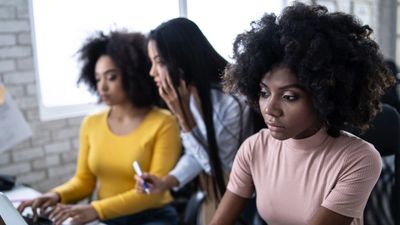 Three focused women working together in an office environment.
