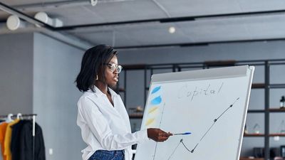 Woman presenting data on a flip chart in an office.