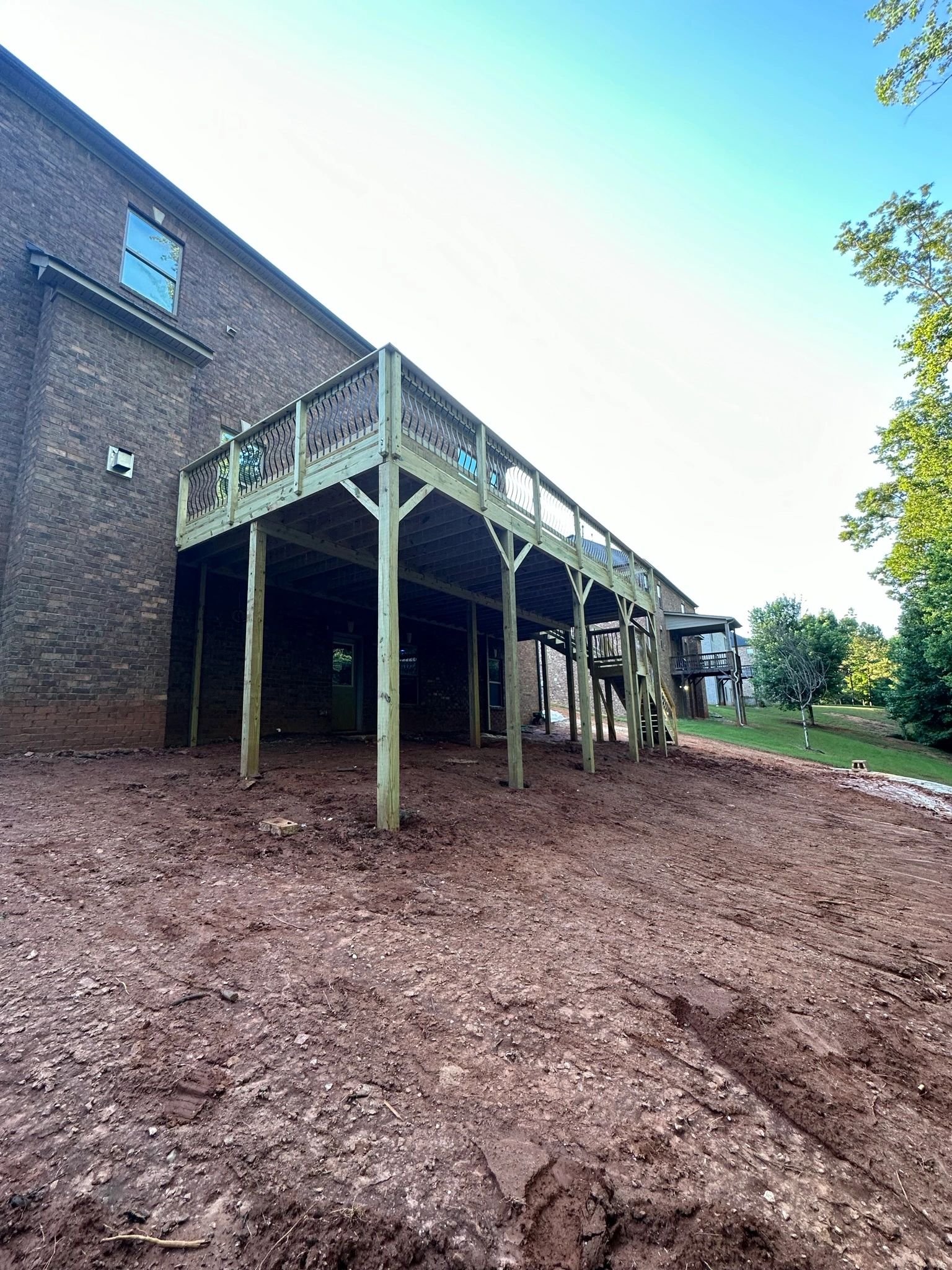 Newly built elevated wooden deck attached to brick house.