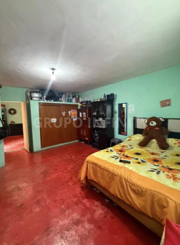 Dormitorio con piso rojo y pared verde.