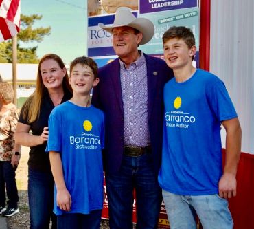 Group photo with two boys in blue shirts and a man in a cowboy hat.