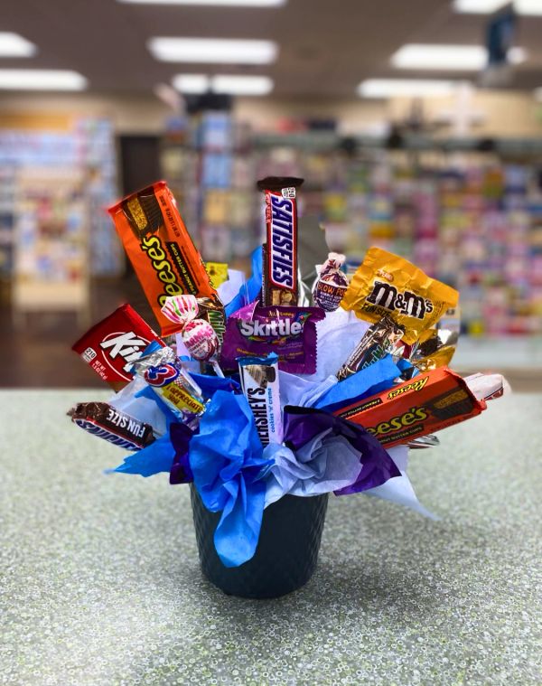 A colorful candy bouquet with various chocolate bars and candies in a black pot.