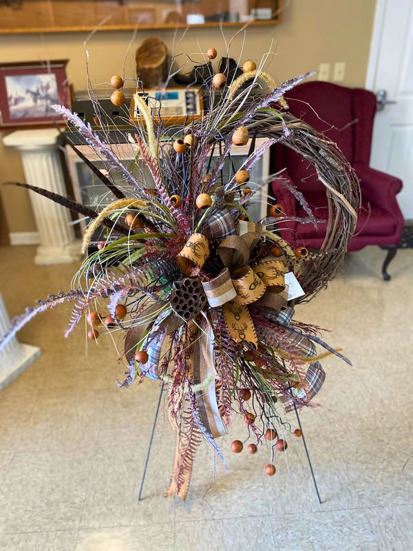 Rustic fall wreath with natural elements and plaid ribbon on stand indoors.