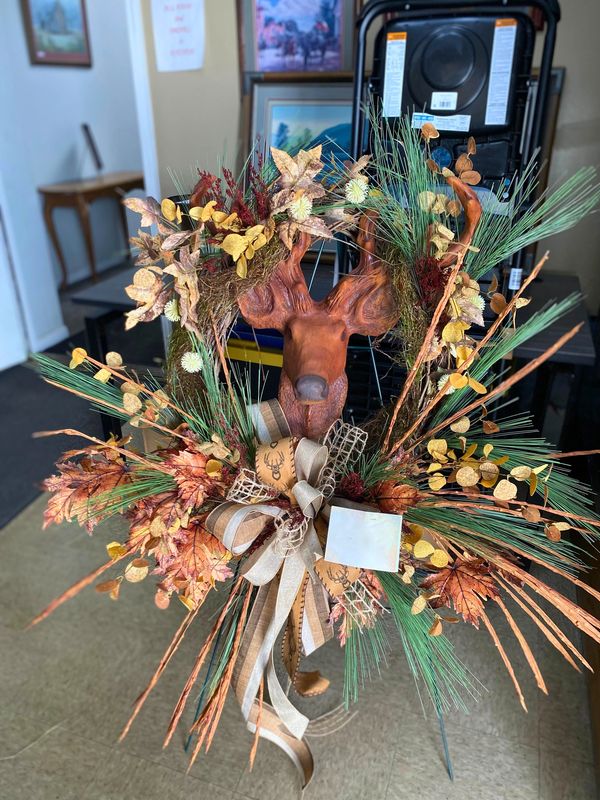Decorative fall wreath with a deer head centerpiece and autumn foliage.